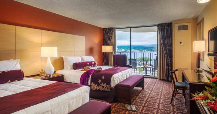 Hilo Hawaiian Deluxe Ocean View Room with view with hat and pareo on the bed