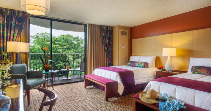 Two beds with burgundy trim, flowers, private lanai with seating